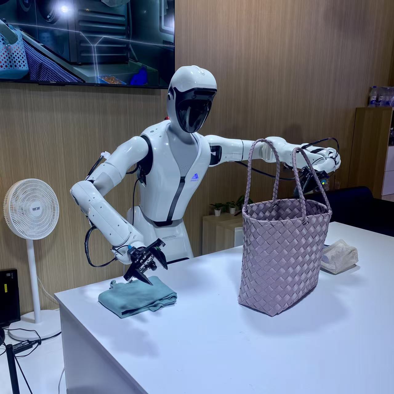 配有夹爪的机器人正在整理衣物 图片来源:财联社记者/摄