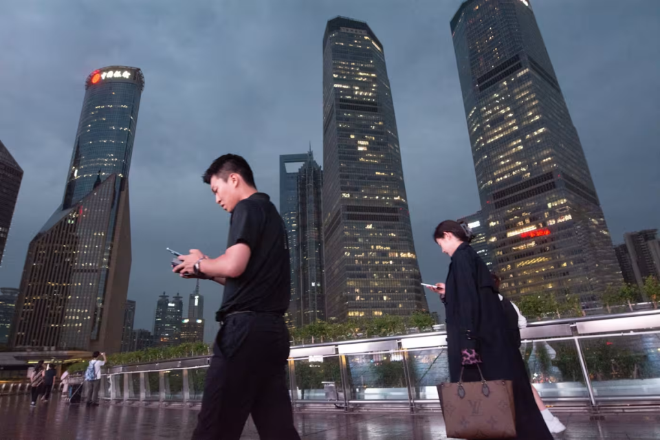 行人边走边看手机，漫步上海街头。尽管人工智能蓬勃发展，但研究表明人们并不想完全摆脱人际交往。 © NurPhoto via Getty Images